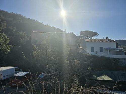 a sun shining over a hill with a house and trees at Chez Choucas Maison e Maisonette - Goelba in Portoferraio