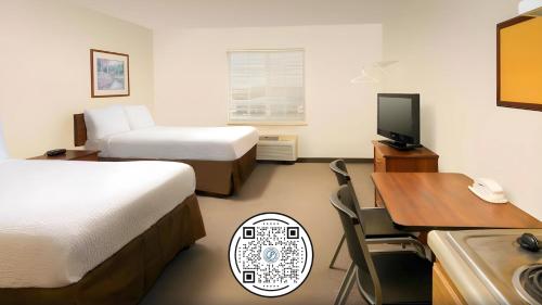 a hotel room with two beds and a desk and a television at WoodSpring Suites Lincoln Northeast I-80 in Lincoln
