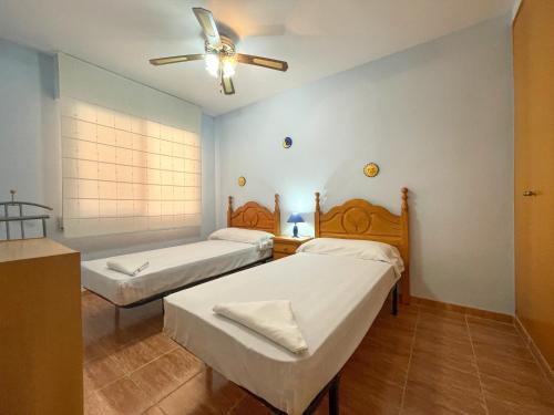 two beds in a room with a ceiling fan at Apartamentos Portofino 3000 in Oropesa del Mar