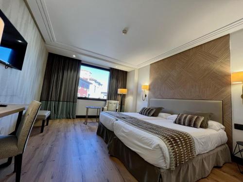 サンタンデールにあるホテル バイアの大型ベッドとテレビが備わるホテルルームです。