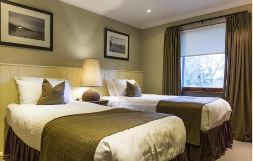 a hotel room with two beds and a window at Cameron House - Lodge 17 - Loch Lomond in Balloch