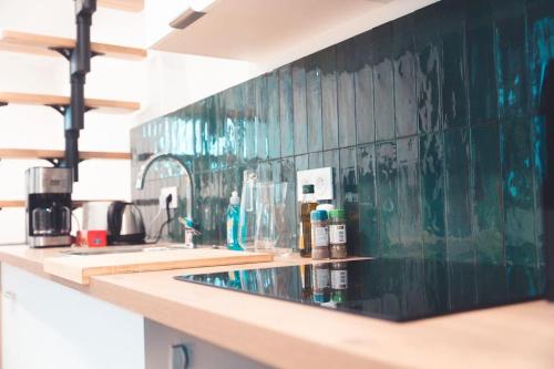 a kitchen counter with a green tiled wall at L’Armoirie, cosy nid douillet in Tours