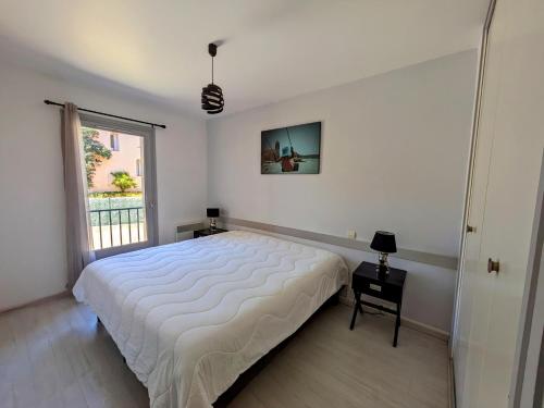 ein weißes Schlafzimmer mit einem großen Bett und einem Fenster in der Unterkunft Appartement central avec parking, terrasse et WIFI in Collioure