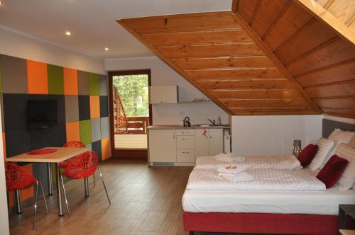 a bedroom with a bed and a table and a kitchen at Apartamenty Lawenda in Rabka