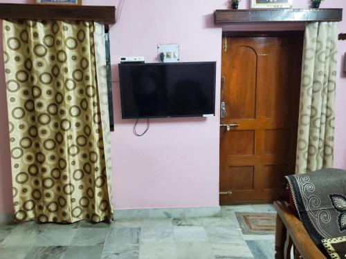 a tv on a wall with curtains and a door at Entire 2bhk ground-floor suite in independent house in Secunderabad
