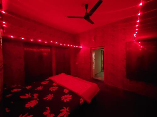 Cette chambre rouge comprend un lit et un ventilateur de plafond. dans l'établissement Entire 2bhk ground-floor suite in independent house, à Secunderābād