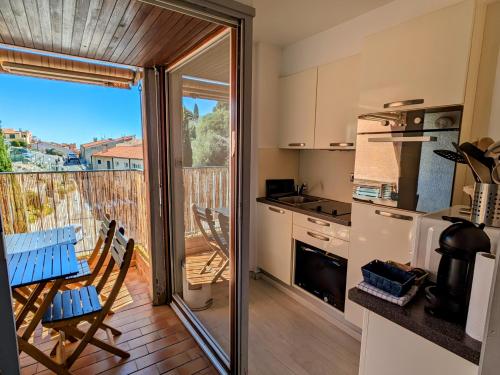 d'une cuisine avec une porte coulissante en verre s'ouvrant sur un balcon. dans l'établissement Appartement central avec parking, terrasse et WIFI, à Collioure