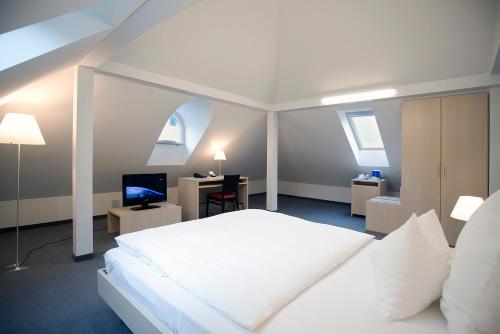 a bedroom with a large white bed and a desk at Hotel Ochsen in Uster