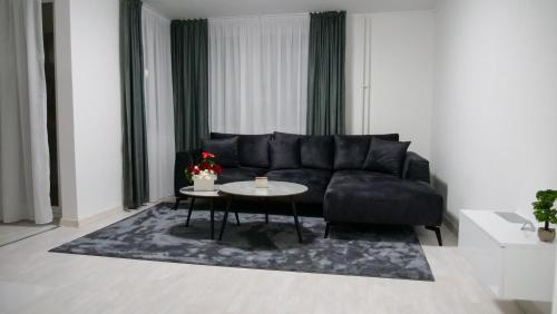 a living room with a black couch and a table at Apartman PLATINUM in Doboj