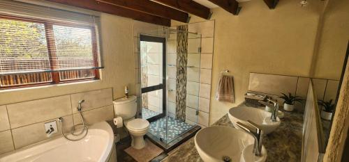 a bathroom with two sinks and a toilet and a shower at Bushveld Jewel - Close to Kruger in Hoedspruit