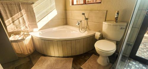 a bathroom with a tub and a toilet and a bath tub at Bushveld Jewel - Close to Kruger in Hoedspruit