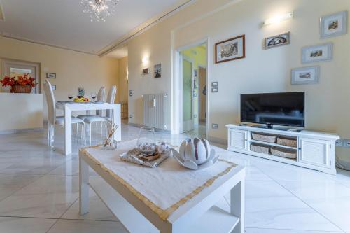 a white living room with a table and a tv at Leandro's House Near Thermal Baths in Montecatini Terme