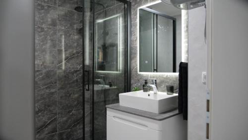 a bathroom with a white sink and a mirror at Apartman PLATINUM in Doboj