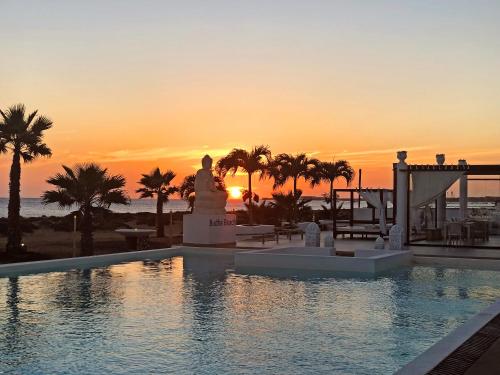 a pool with a statue in front of a sunset at Hotel LIVVO Budha Beach in Santa Maria