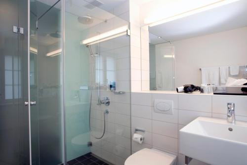 a bathroom with a shower and a toilet and a sink at Hotel Ochsen in Uster
