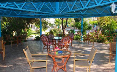 a group of chairs and tables under a blue umbrella at Hotel Dimitra Sun in Archangelos