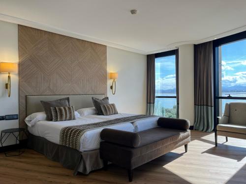 a bedroom with a large bed and a chair at Hotel Bahía in Santander