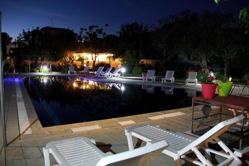 a pool with white lounge chairs and a table and a group ofitures at Hotel Dimitra Sun in Archangelos