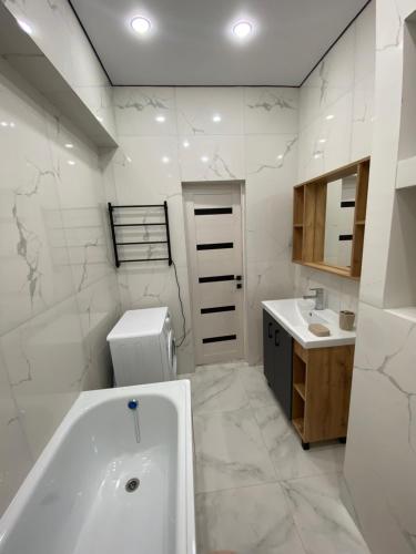 a white bathroom with a tub and a sink at K7 Family in Atyraū
