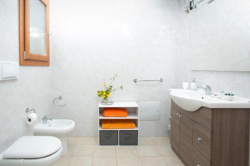 uma casa de banho branca com um lavatório e um WC e um lavatório em B&B Montedarena em Pulsano