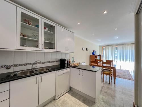 a kitchen with white cabinets and a dining room at Casa Coração de Viana - Near the Beach Apartment in Viana do Castelo