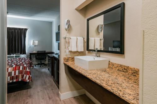 a hotel room with a sink and a bedroom at Red Roof Inn San Antonio - Seaworld Northwest in San Antonio