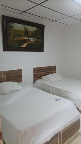 two beds in a room with a painting on the wall at Hotel La Mata in La Mata