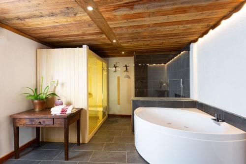 ein Badezimmer mit einer weißen Badewanne und einer Holzdecke in der Unterkunft Casa Girod - Rascard in Issime