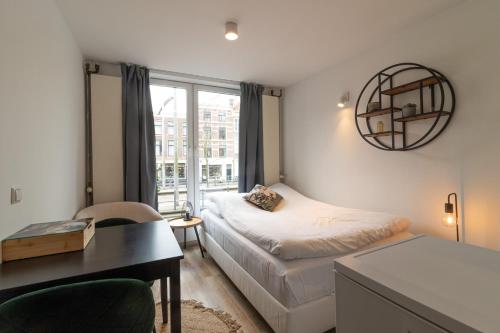 1 dormitorio con cama, escritorio y ventana en Homey Studios - City Centre en The Hague