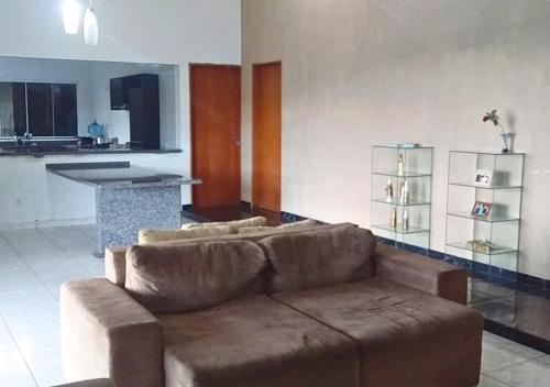 a living room with a brown couch and a kitchen at Chácara Jacoob em Itatiba Capacidade p/ 40 Pessoas in Itatiba