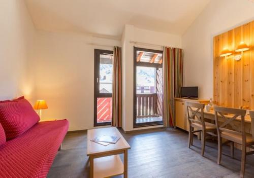 a living room with a red couch and a table at travelski home classic - Résidence La Muzelle in Les Deux Alpes