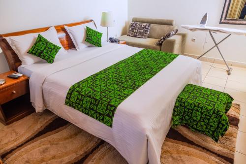 a bedroom with a large bed with a green blanket at One Click Hotel in Kigali