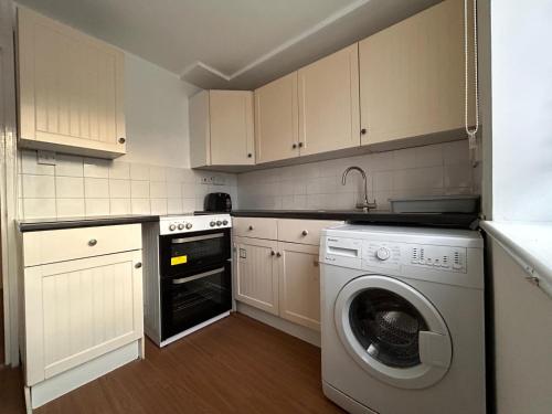 a kitchen with a washing machine and a washer at Spacious one bed flat in eastlondon with parking and free wifi in Goodmayes