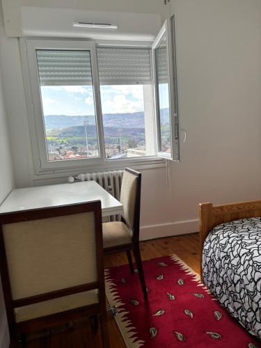 1 dormitorio con mesa, cama y ventanas en Modhumita, en Chambéry