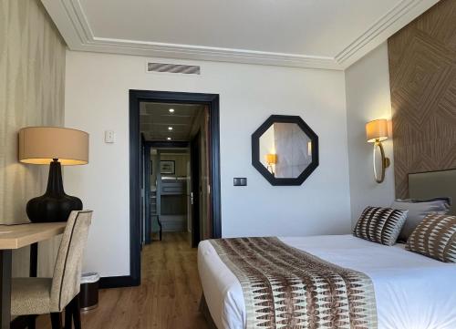 a hotel room with a bed and a table and a mirror at Hotel Bahía in Santander
