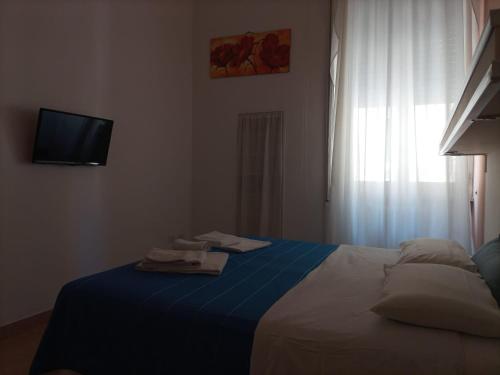 a bedroom with a bed with a blue blanket and a television at H Central Lecce in Lecce