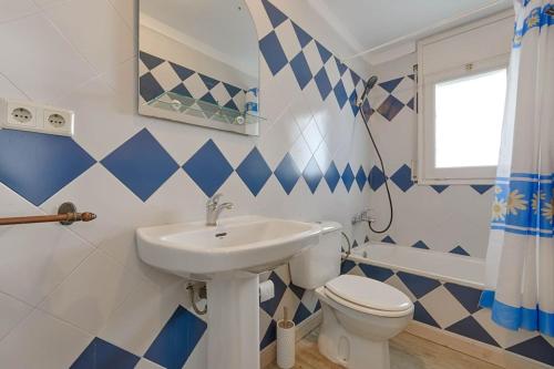 baño azul y blanco con lavabo y aseo en Acogedor y luminoso apartamento con dos habitaciones Planta 2 N4, en Roses