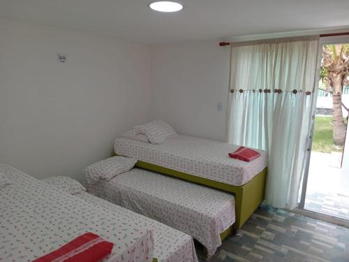 two twin beds in a room with a window at Sharick Beach House in Tubará