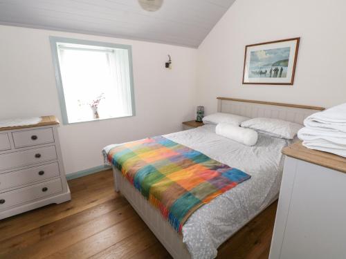 a bedroom with a bed with a rainbow blanket at Freemans Cottage in Enniscrone