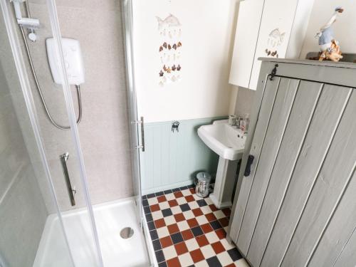 a small bathroom with a shower and a sink at Freemans Cottage in Enniscrone