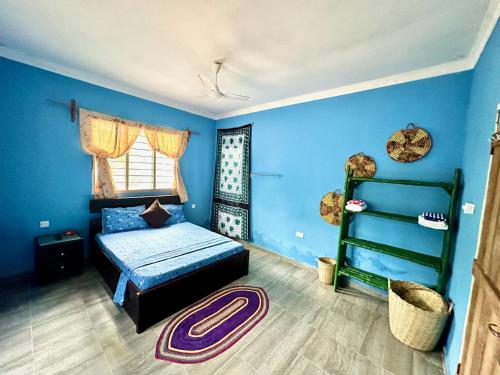 Dormitorio con paredes azules, cama y estante en Mama's House en Kibweni