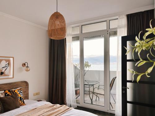 a bedroom with a bed and a balcony with a table at Sunset Apartment in Batumi