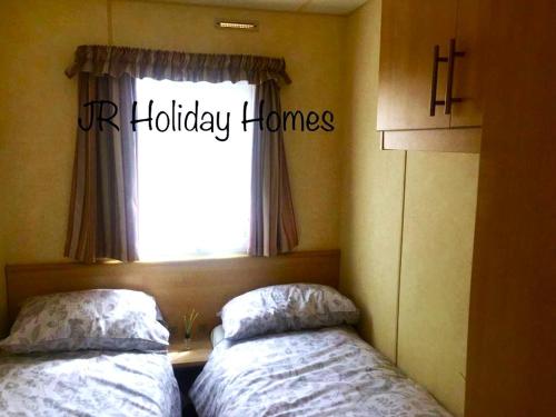 a bedroom with two beds in front of a window at J.R. Holiday Homes in Clacton-on-Sea