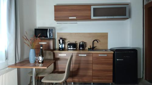 a small kitchen with a table and a refrigerator at Apartmány u jezera Fami*** in Doksy
