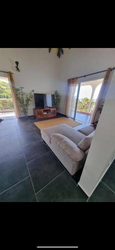 a living room with a couch and a television at Maison de charme à Gourbeyre avec vue mer et montagnes in Gourbeyre