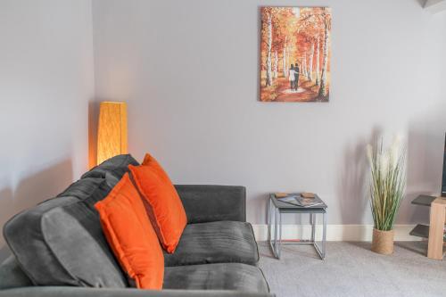 a black couch with orange pillows in a living room at The Apartments Coniston in Coniston