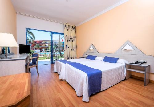Habitación de hotel con cama, escritorio y ventana en SBH Fuerteventura Playa, en Costa Calma