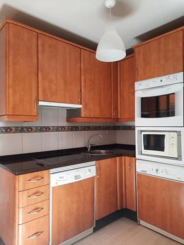 a kitchen with wooden cabinets and white appliances at Apartamento Candelaria in Zamora