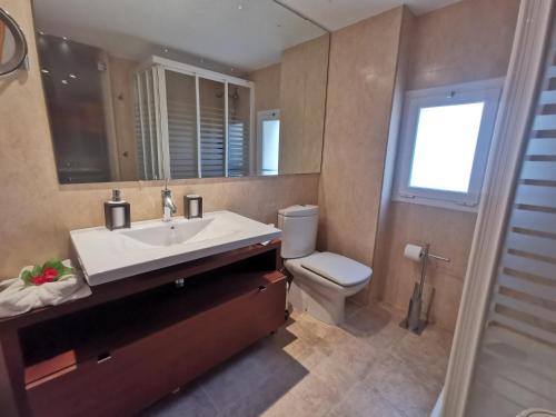 een badkamer met een wastafel, een toilet en een spiegel bij Apartamento Platja d'Aro, 3 dormitorios, 5 personas - ES-209-42 in Platja  d'Aro