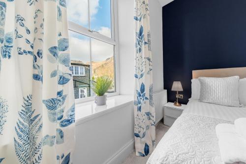 a blue and white bedroom with a bed and a window at The Apartments Coniston in Coniston